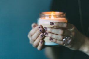 Eine brennende Kerze im Glas gehalten von 2 Händen
